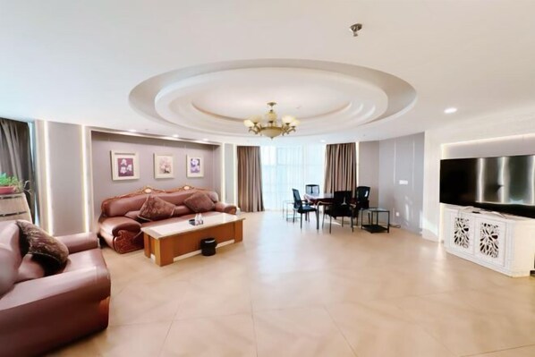 A modern living room with a sofa, coffee table, TV, and dining area. - Jiangsu Hotel (Yining City)