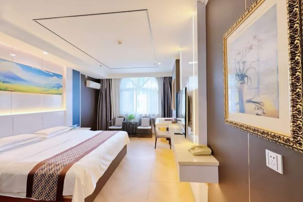 Una camera d'albergo con un letto, una scrivania, una sedia, una televisione e un quadro appeso al muro.