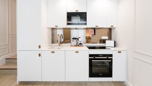 A modern kitchen with white cabinetry, a built-in oven, a coffee machine, and a sink. - GuestReady - A charming studio in downtown (Porto)