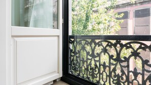 A window with a white frame and a black ornate metal railing. - GuestReady - A charming studio in downtown (Porto)