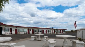 A motel with a row of rooms, outdoor tables, and an American flag. - Ala Cozy Motel (Coulee City)