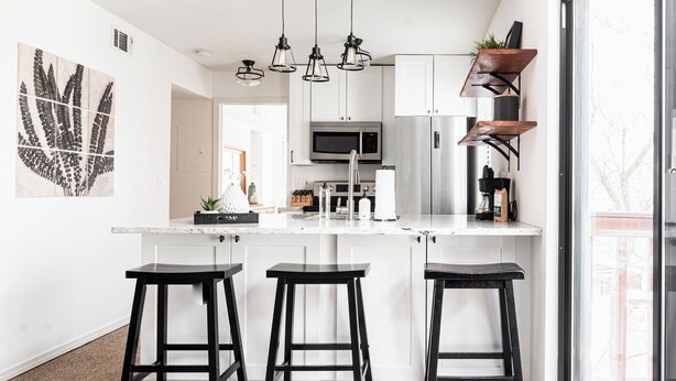 A modern kitchen with a central island, stainless steel appliances, and black bar stools. - DTC One Bed Condo, Pool, Gym, Comfort (Greenwood Village)