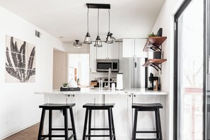 A modern kitchen with a central island, stainless steel appliances, and black bar stools. - DTC One Bed Condo, Pool, Gym, Comfort (Greenwood Village)