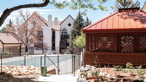 A residential area with a fenced yard, a small gazebo, and a building with a red roof. - Cozy Studio Unit in DTC (Greenwood Village)