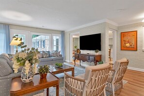 A spacious living room with a large flat-screen TV, a sofa set, a coffee table, and wicker chairs. - Pool-Sleeps 20-Stylish- 5 mins to downtown Southern Pines- Close to Pinehurst (Southern Pines)