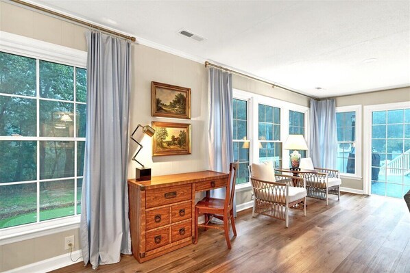 A spacious room with a wooden desk, a chair, a dining table with chairs, and large windows with curtains. - Pool-Sleeps 20-Stylish- 5 mins to downtown Southern Pines- Close to Pinehurst (Southern Pines)