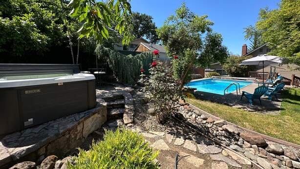 A backyard with a hot tub, a swimming pool, and a patio area with chairs. - Medford Home and 2 Condos With Pool and Hot tub (Medford)