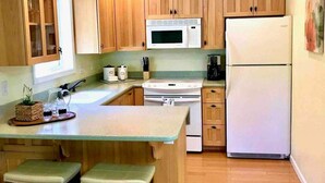 A compact kitchen with wooden cabinets, a central island, and a double-door refrigerator. - Medford Home and 2 Condos With Pool and Hot tub (Medford)