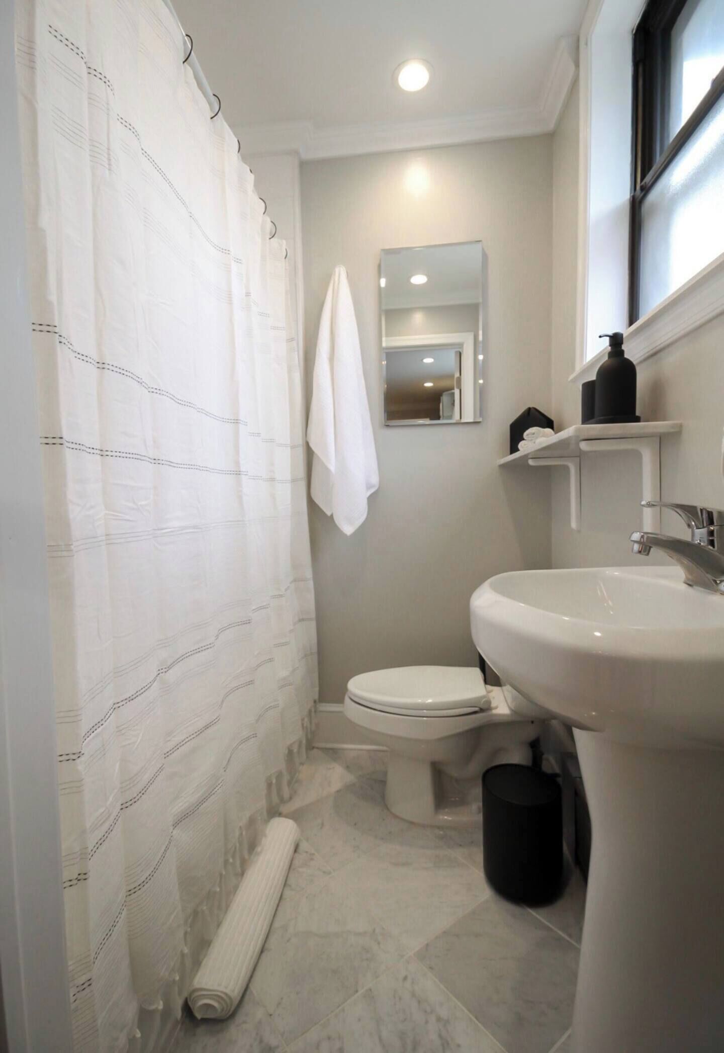 Un baño con inodoro, lavamanos y cortina de ducha.