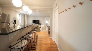 A modern kitchen with a long countertop, bar stools, and pendant lighting. - 405 S 20th  (Philadelphia)