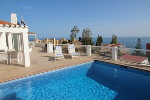A swimming pool with lounge chairs and a view of the sea. - Villa Arriba Fuengirola (Fuengirola)