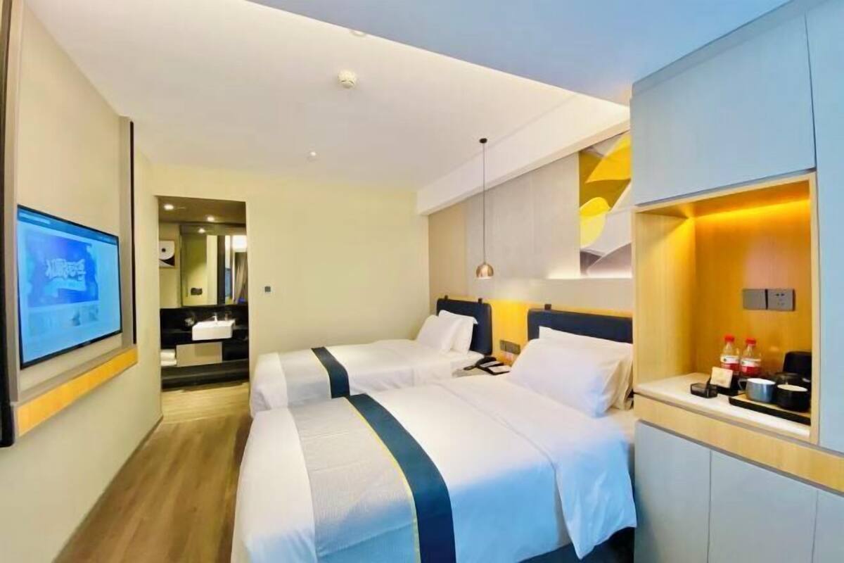 Une chambre d’hôtel avec deux lits, une télévision, un bureau avec une lampe et un miroir.