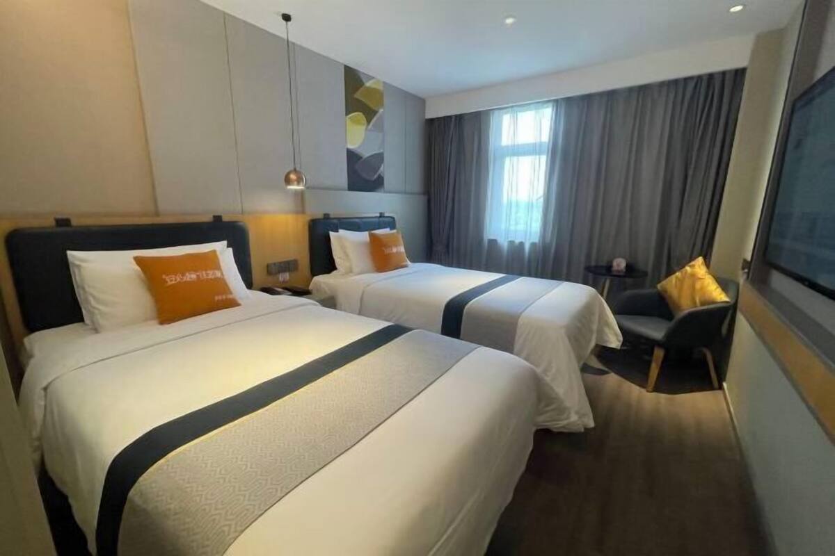 Une chambre d’hôtel avec deux lits, chacun doté d’une tête de lit, d’une petite table et d’une chaise.