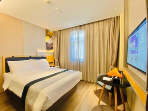 Une chambre d’hôtel équipée d’un lit, d’un bureau, d’une chaise, d’une télévision et d’une fenêtre avec des rideaux.