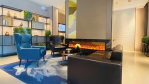 A modern living room with a fireplace, blue armchairs, and a bookshelf with decorative items. - Homeinn Selected Hotel (Beijing Beixinqiao Nanluoguxiang) (Beijing)