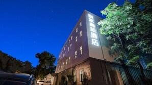 A building with illuminated signage, surrounded by trees and parked cars. - Homeinn Selected Hotel (Beijing Beixinqiao Nanluoguxiang) (Beijing)