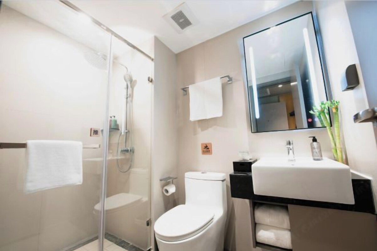A modern bathroom with a glass-enclosed shower, a white toilet, a sink with a mirror, and a towel rack.