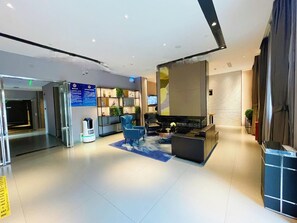 A modern hotel lobby with a reception desk, seating area, and a large screen. - Homeinn Selected Hotel (Beijing Beixinqiao Nanluoguxiang) (Beijing)