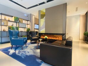 A modern living room with a fireplace, black leather furniture, and a bookshelf with decorative items. - Homeinn Selected Hotel (Beijing Beixinqiao Nanluoguxiang) (Beijing)