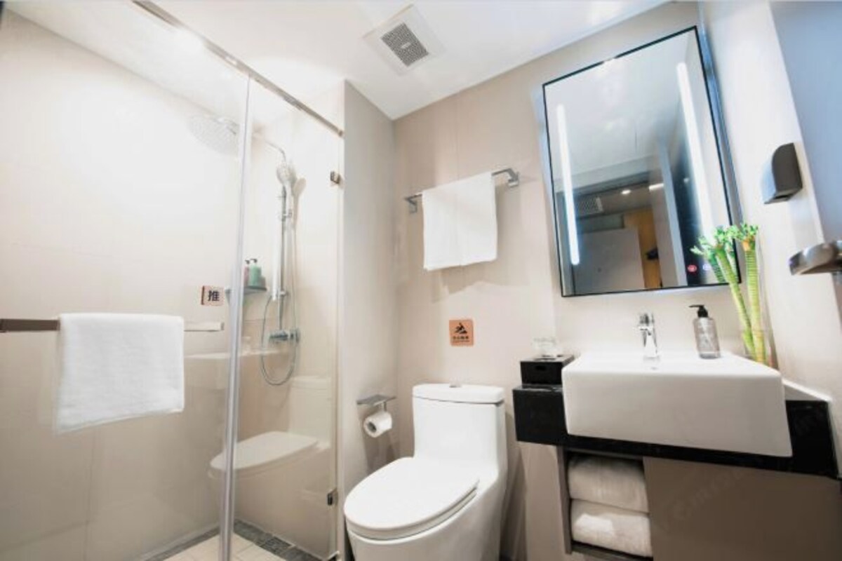 A modern bathroom with a glass-enclosed shower, a white toilet, a sink with a mirror, and a towel rack.