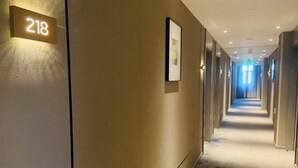 A hotel hallway with a carpeted floor, a number sign '218' on the wall, and framed pictures. - Homeinn Selected Hotel (Beijing Beixinqiao Nanluoguxiang) (Beijing)