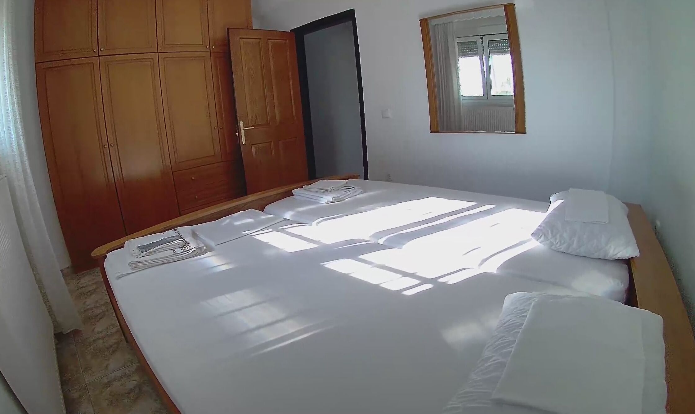 A bedroom with a bed, a wardrobe, and a window.