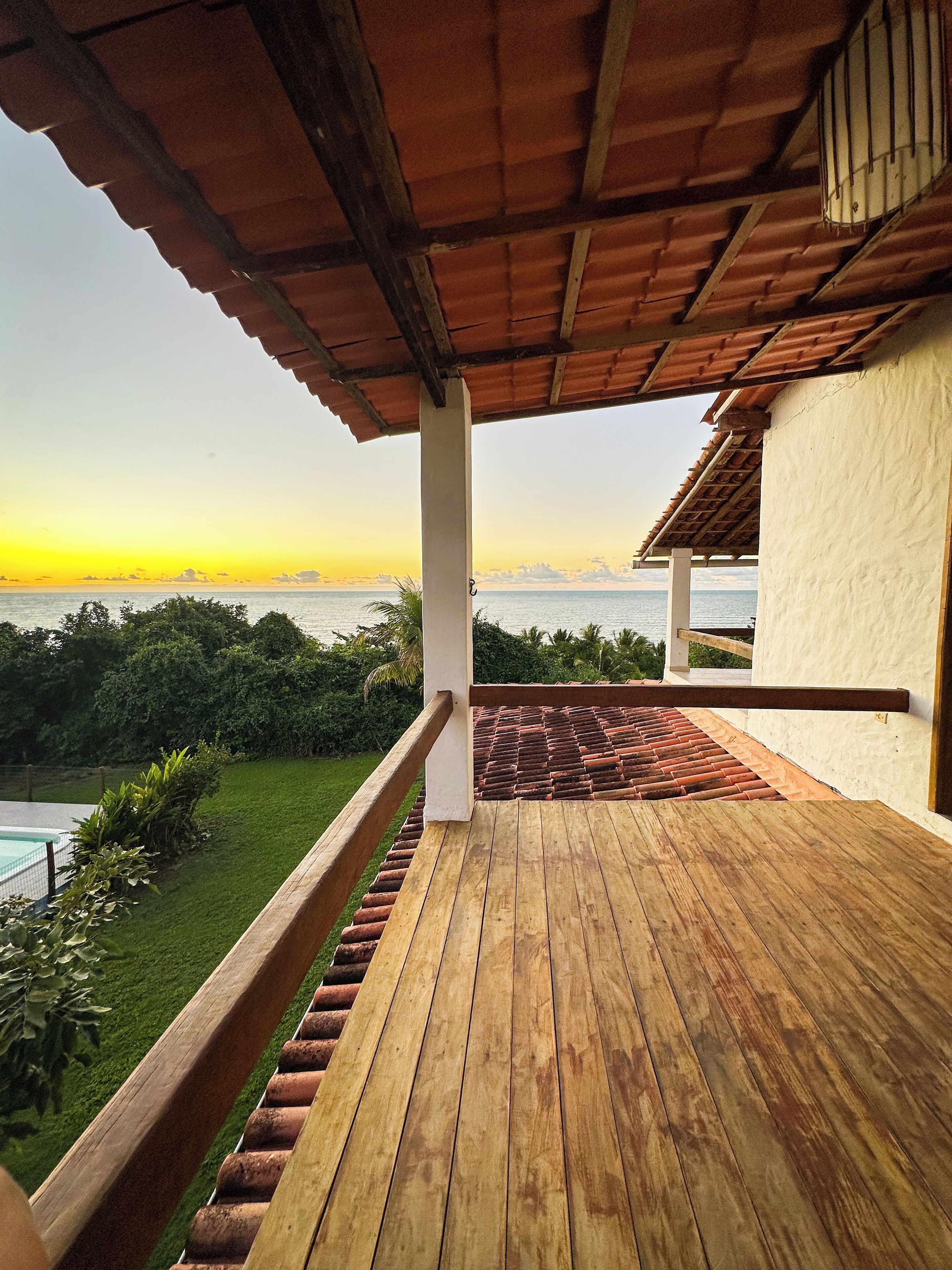 A wooden deck with a view of the sea at sunset.