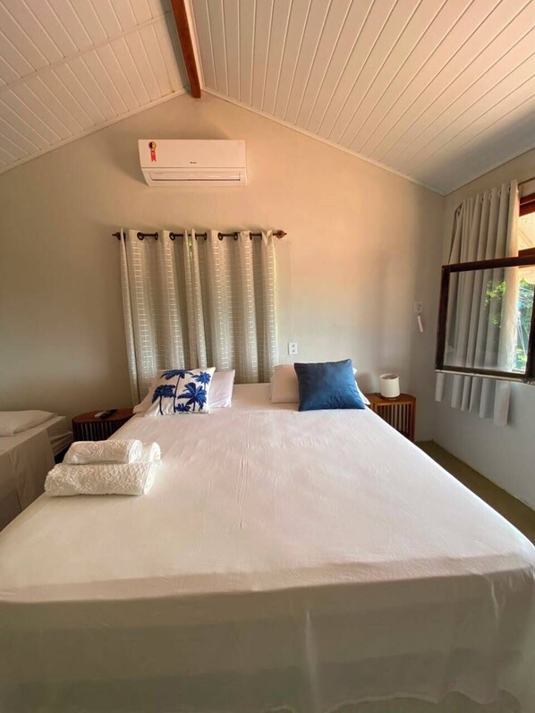 Une chambre d’hôtel avec un grand lit, un ventilateur de plafond, une fenêtre avec des rideaux et une table de chevet.