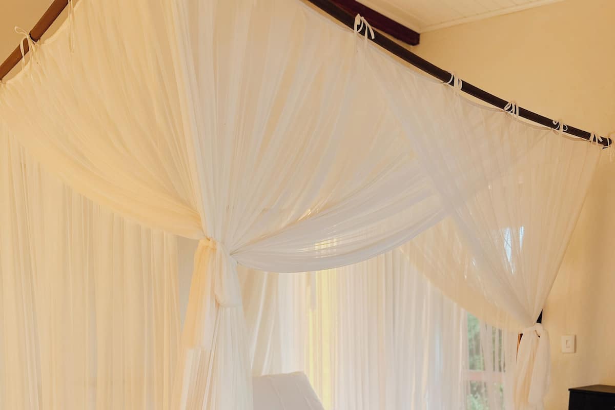 A four-poster canopy bed with a quilted mattress and a white bedspread.