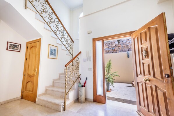Una escalera con barandilla decorativa, una puerta de madera y vistas al exterior.