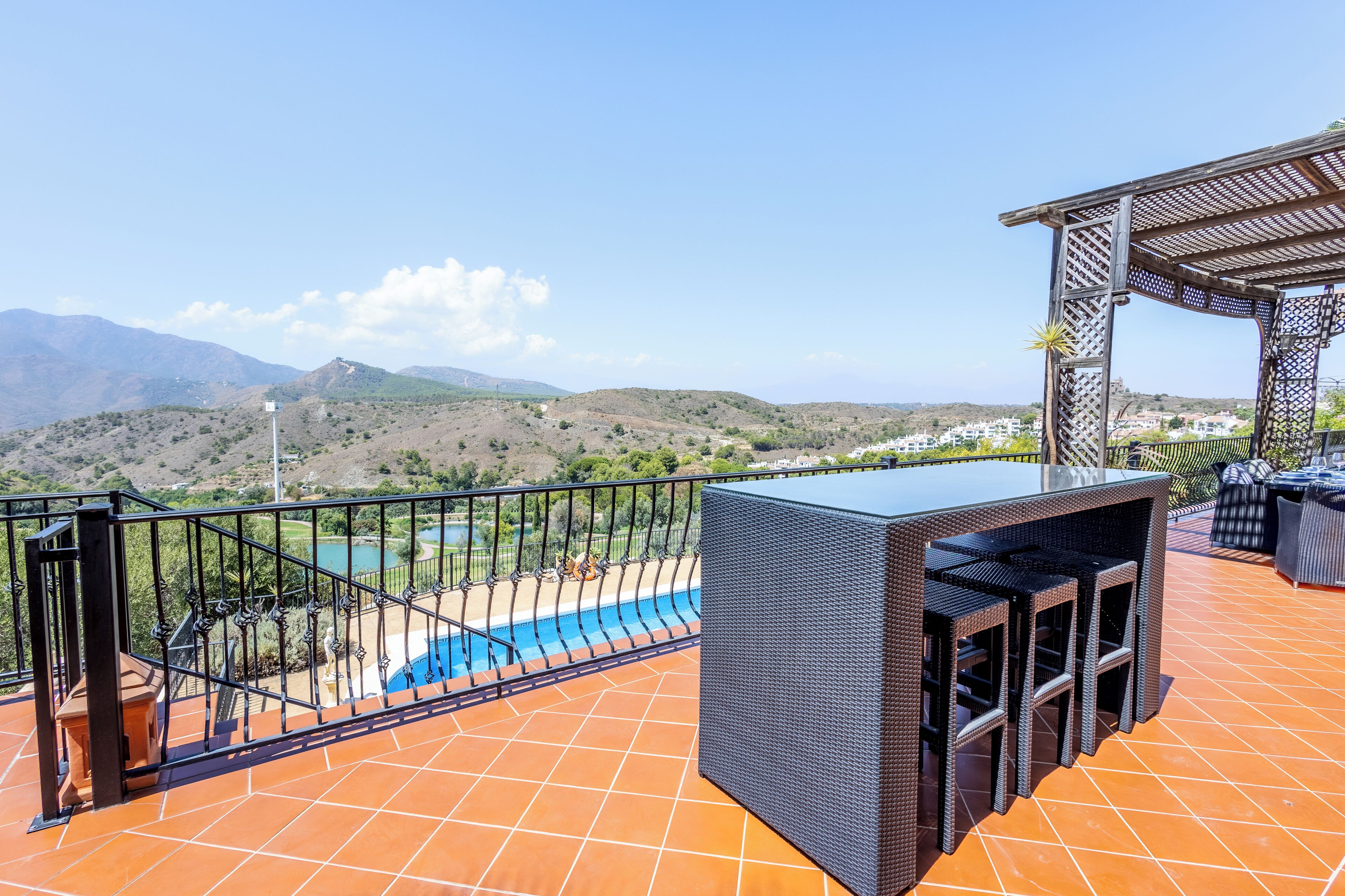 A terrace with a pool, outdoor furniture, and a view of hills and mountains.