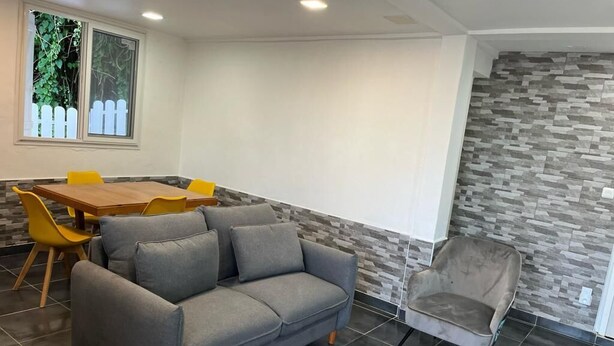 A modern living room with a grey sofa, yellow chairs, a wooden table, and a grey armchair. - Bienvenue au Chacha (FORT-DE-FRANCE)