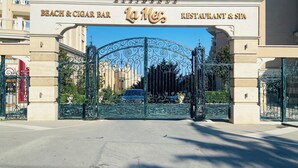 Ein hoteleigener Eingang mit Tor, mit Schildern, auf denen 'Beach & Cigar Bar' und 'La Mer Restaurant & Spa' steht.