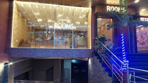 Ein Hotel Eingang mit Glasfassade, auf der 'Signature Rooms' steht, und einer Treppe mit blauer Beleuchtung.