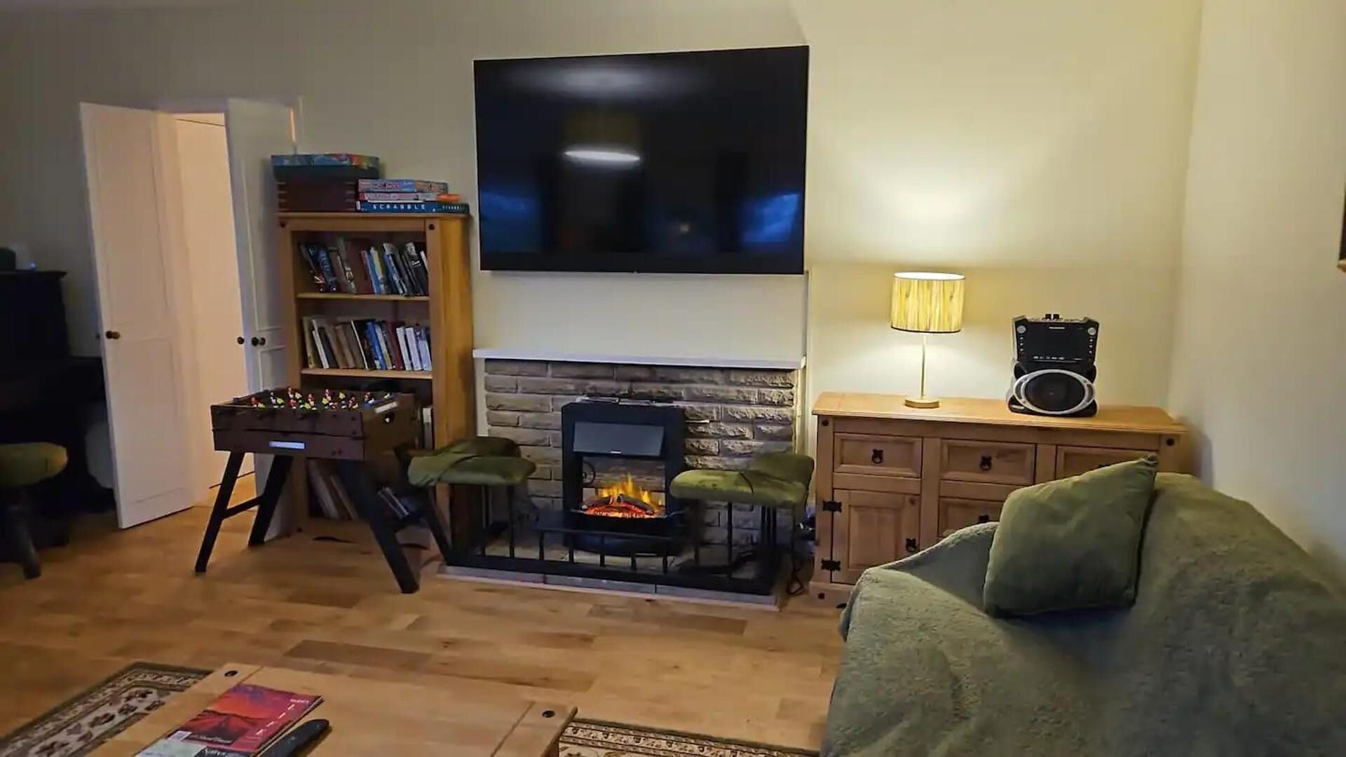 A living room with a fireplace, a television mounted on the wall, a bookshelf, and a sofa.
