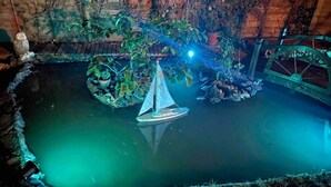 A model boat in a pond with a bridge and foliage. - Mersea Island Retreat - 4 Bedroom House (Colchester)