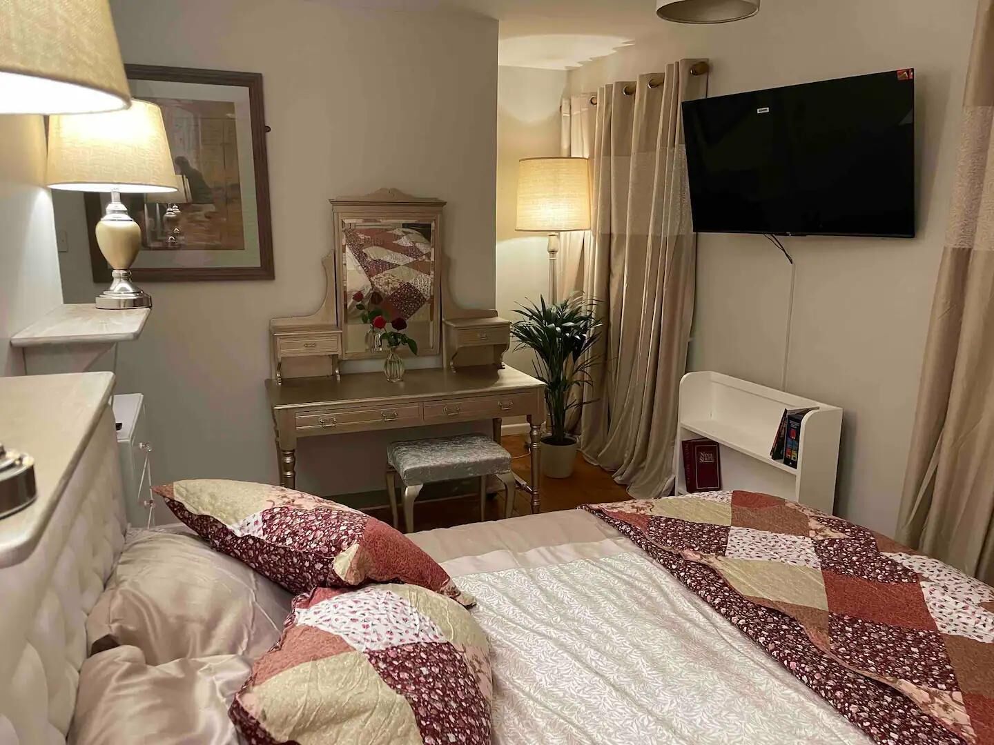 A hotel room with a bed, a desk, a chair, a television, and a mirror.