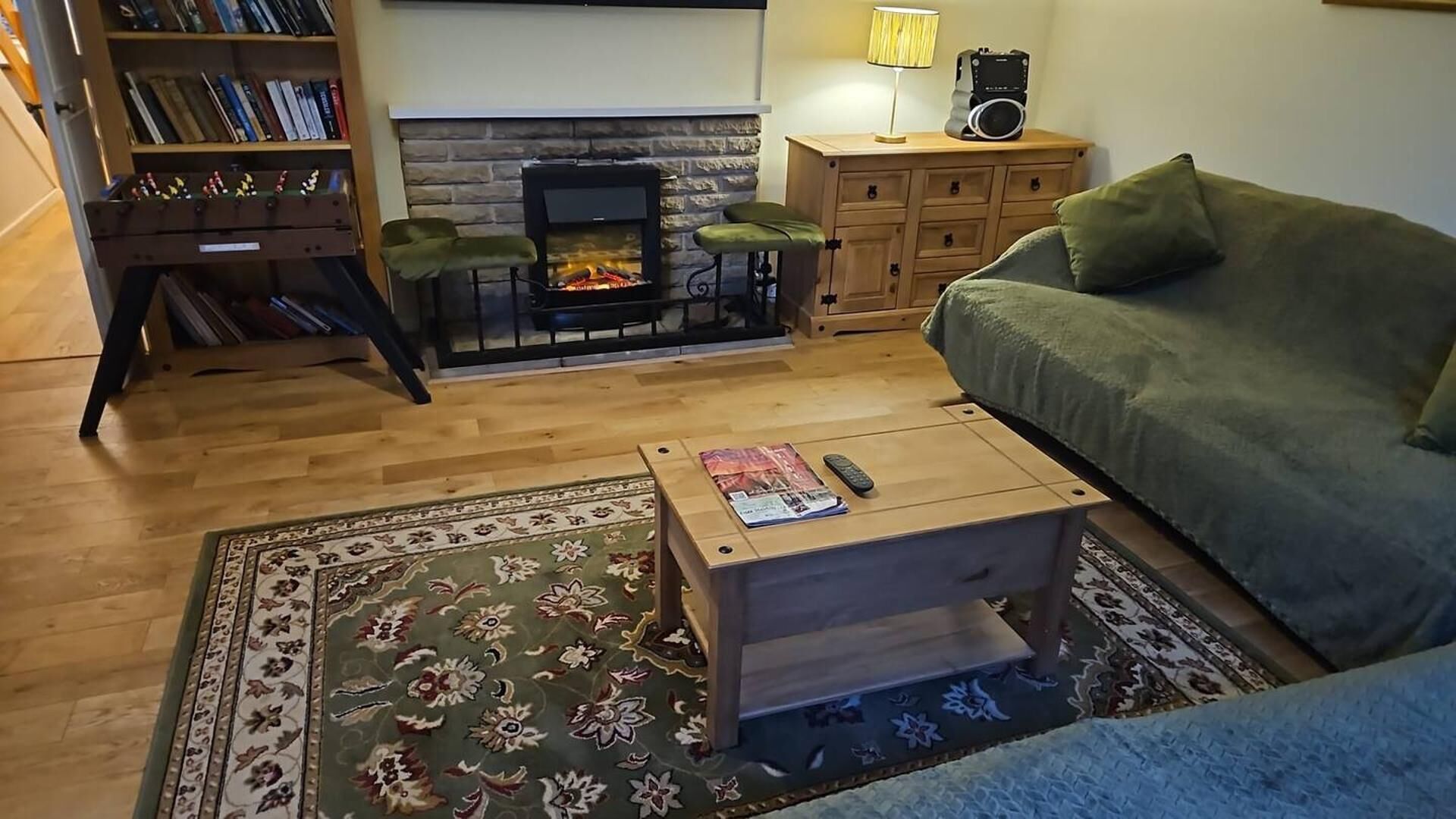 Ein gemütliches Wohnzimmer mit Kamin, einer Couch, einem Couchtisch und einem Bücherregal.