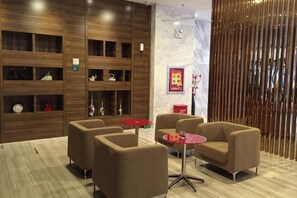 A modern hotel lobby with wooden shelving, comfortable seating, and a marble wall.