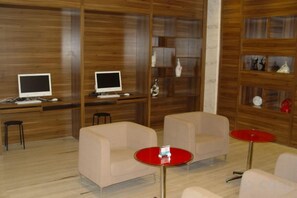 A modern interior with two sofas, a red table, and two computer monitors on a wooden wall.