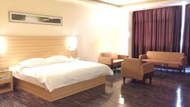 A hotel room with a wooden bed, a sofa, a chair, and a desk.