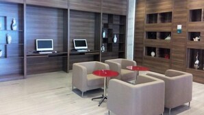 A modern lounge area with sofas and small tables, a laptop on a desk, and decorative items on shelves. - Nileke Echarm Hotel (Nilka County)