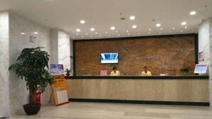 A reception area with marble walls, a large plant, and a TV screen.