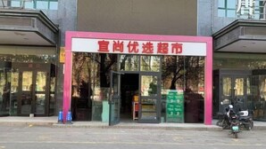 A building with a pink and white sign, glass doors, and a motorcycle parked outside.