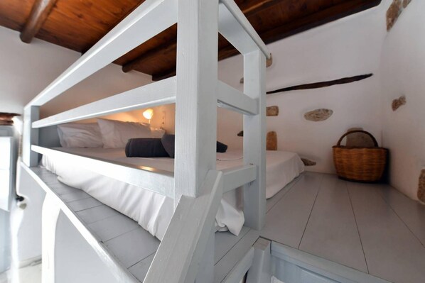 Un lit superposé avec une échelle en bois, une lampe de chevet et un panier en osier posé sur le sol.