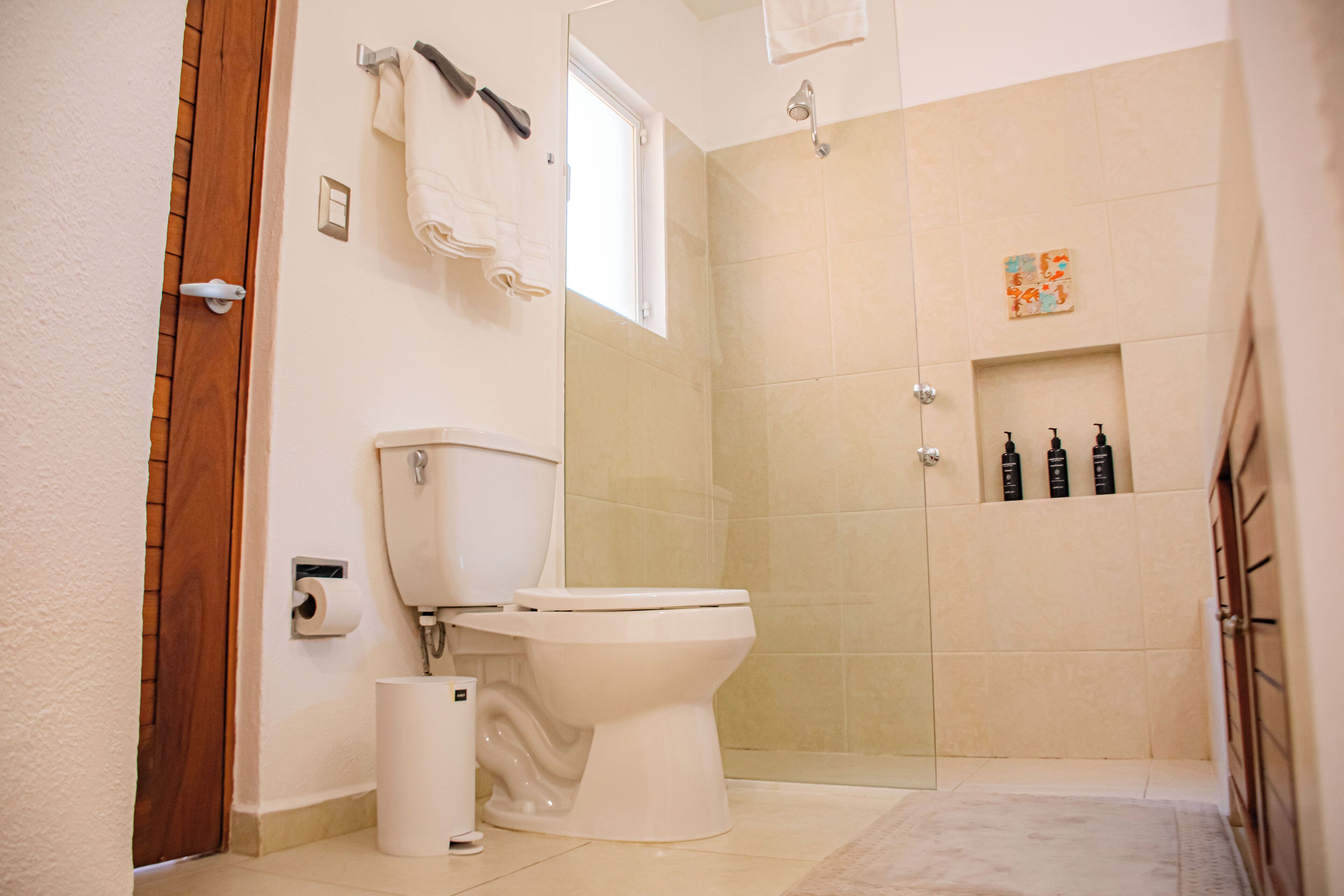 A bathroom with a toilet, a shower, and a towel rack.