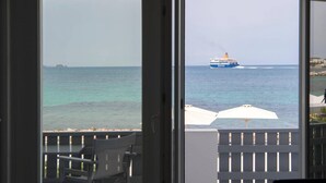 A view from a balcony with a ship in the distance, a white umbrella, and a chair. - Parikia s Seaside House (Paros)