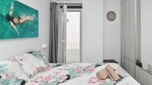 A bedroom with a bed, a painting, an air conditioning unit, a sliding door, and a motivational wall plaque. - Parikia s Seaside House (Paros)
