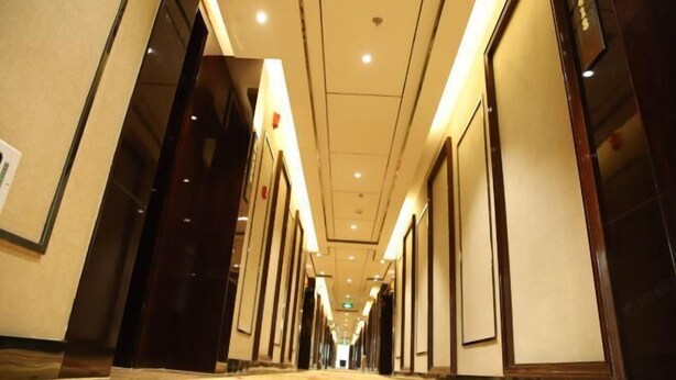 A hotel corridor with a carpeted floor, doors on both sides, and recessed lighting on the ceiling. - Fengda Vista Hotel (Wuwei No.2 Middle School Pedestrian Street) (Wuwei)