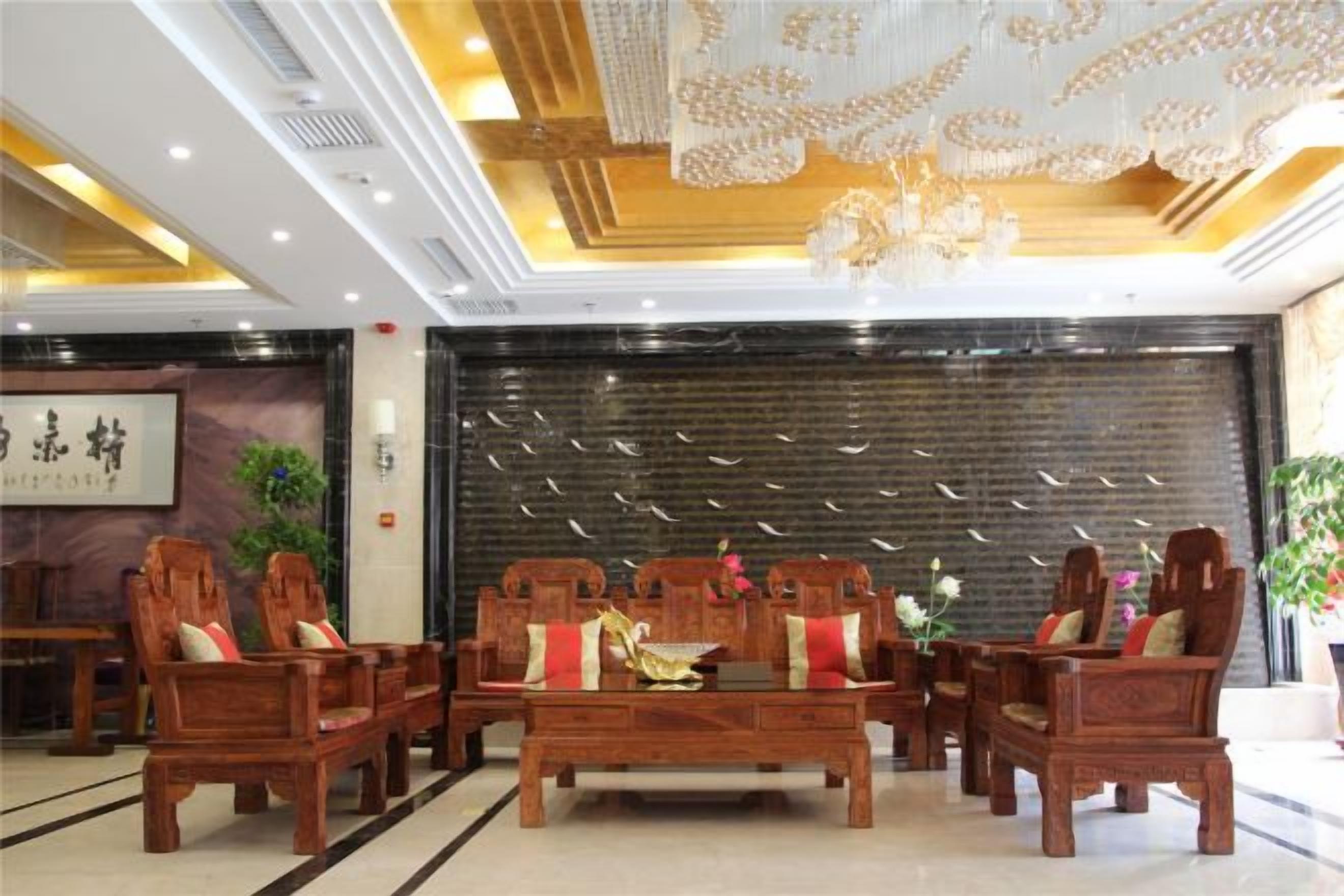 A lobby with wooden furniture, a black wall with vertical lines, and a chandelier.